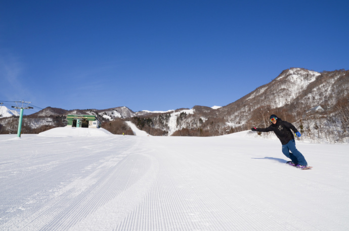 鐘の鳴る丘ゲレンデでスノーボードを楽しむ人の写真