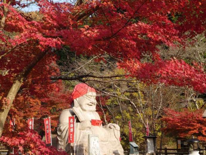 「通宝山彌勒寺」境内の巨大な布袋尊像と紅葉（秋）