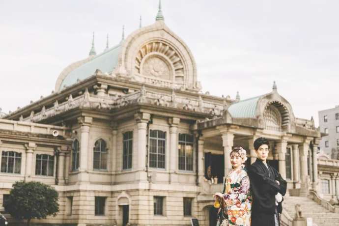 築地本願寺を背景にポーズをとる和装の新郎新婦