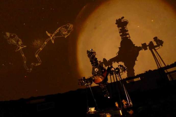 スクリーンに、投影した星座と一緒に投影機のシルエットが写っている写真
