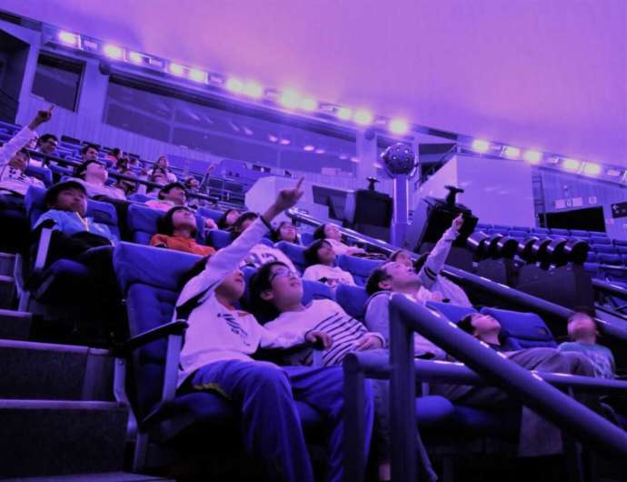 埼玉県さいたま市にある「さいたま市宇宙劇場」でプラネタリウム番組を視聴する人々