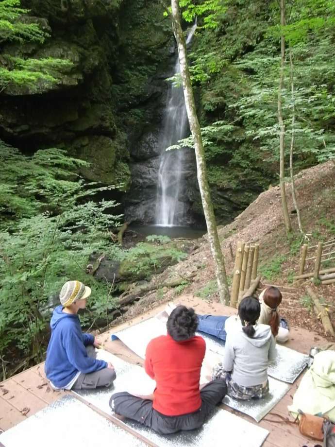 上野村森林セラピーでしか訪れることができないオボロカヤの滝の前でリラックスする人々