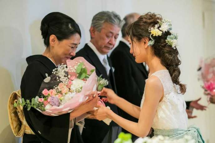 披露宴の結びに、泣きながら母親へ花束を渡す新婦の写真