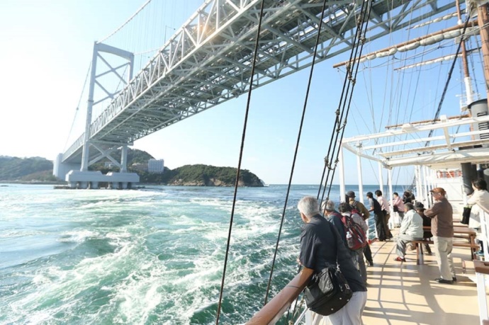 大鳴門橋をくぐるクルーズ船「日本丸」のオープンデッキでくつろぐ乗船客