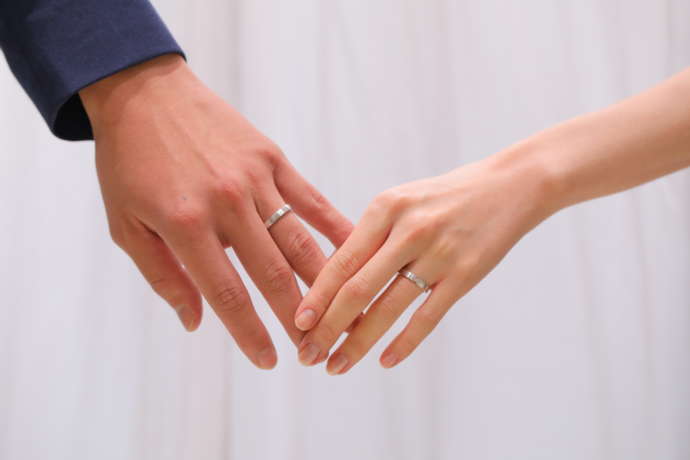 ヴェールの結婚指輪を身に着けているカップル