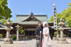若松惠比須神社の本殿を背景に佇む和装の新郎新婦