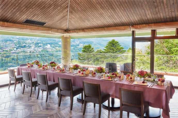 濃い落ち着いたピンク色のテーブルクロスと装花に彩られた披露宴のテーブルの写真