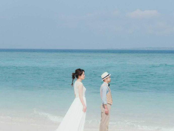 沖縄の美しい海を見つめる新郎新婦