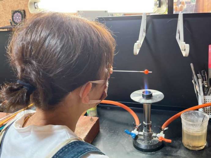 「色伝師 乃和」の「ガラス工芸」制作体験のバーナーワークでとんぼ玉を作る女性