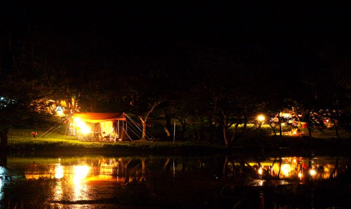 明かりが灯る夜の駒出池キャンプ場の湖畔サイト