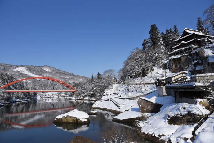 雪の中の圓藏寺と只見川に架かる赤い橋