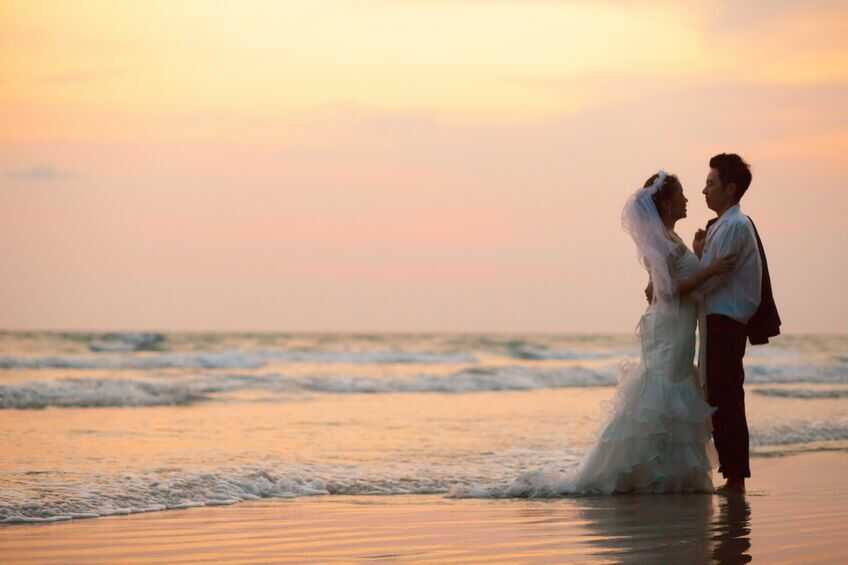 夕日に照らされた海で抱き合っているカップルの写真