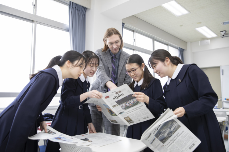 ネイティブの先生と英字新聞を読む愛徳学園中学校・高等学校の生徒たち