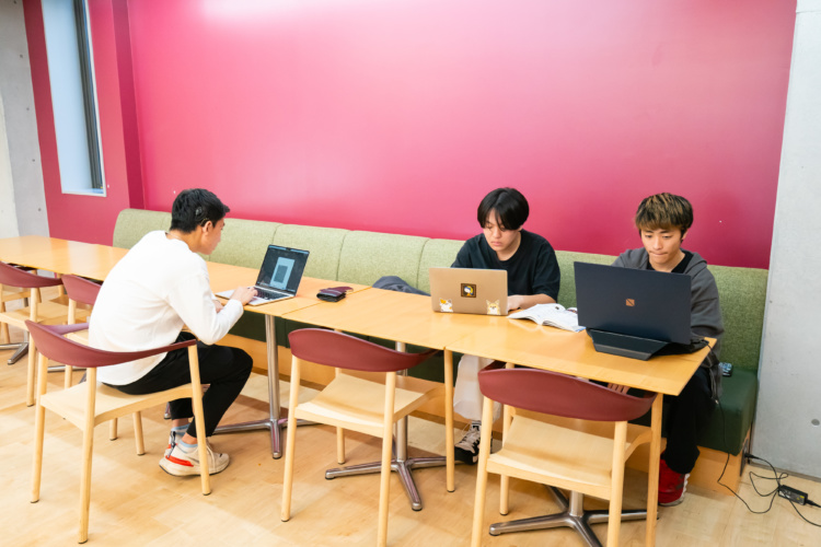 ドルトン東京学園の生徒3名がカフェテリアでラボの課題に取り組むようす