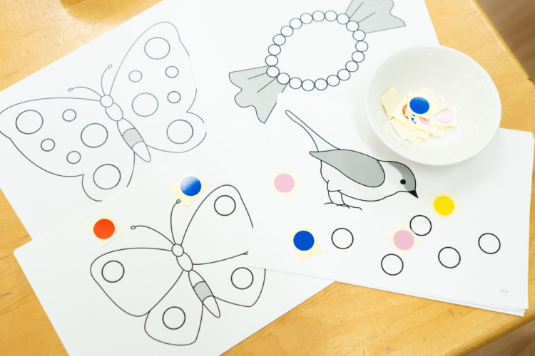 机の上に置いてある蝶々や鳥の絵が描かれたシール貼りの台紙と丸い形のシール