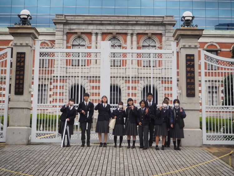 関西大倉中学校・高等学校の生徒たちが裁判所の外で記念撮影するようす