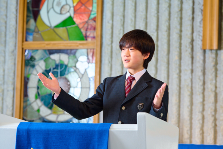 聖望学園中学校の礼拝堂で教壇に立つ男子生徒