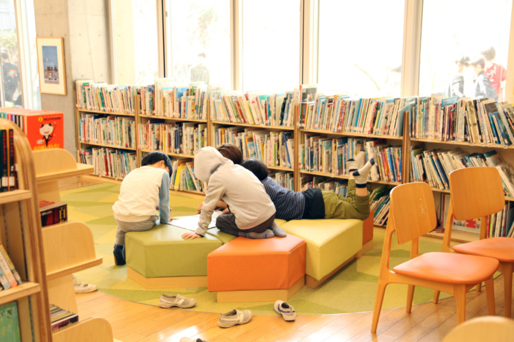 成城学園初等学校の「図書のへや」のソファで児童らが本を読むようす