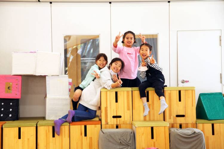 成城学園初等学校の児童4名が箱に登って遊びの時間を過ごすようす
