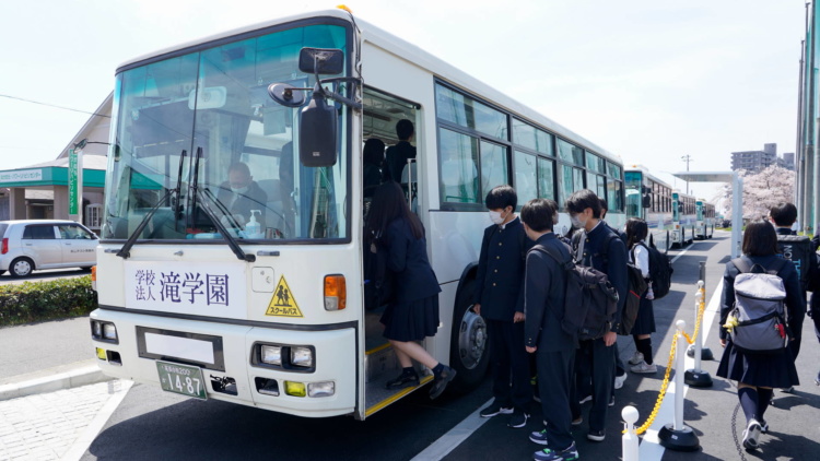 「滝中学・滝⾼等学校」のスクールバスに乗車する生徒
