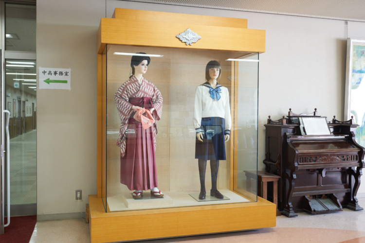 東京女学館中学校・高等学校の創立当時の服装と現在の制服が飾られている写真